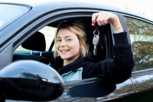 Young girl happy holding car key seated in her new car