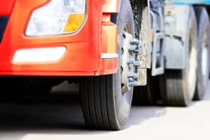 Truck driving on road, close-up to truck front wheel and headlight parts