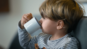 Young baby eating out of a cup.