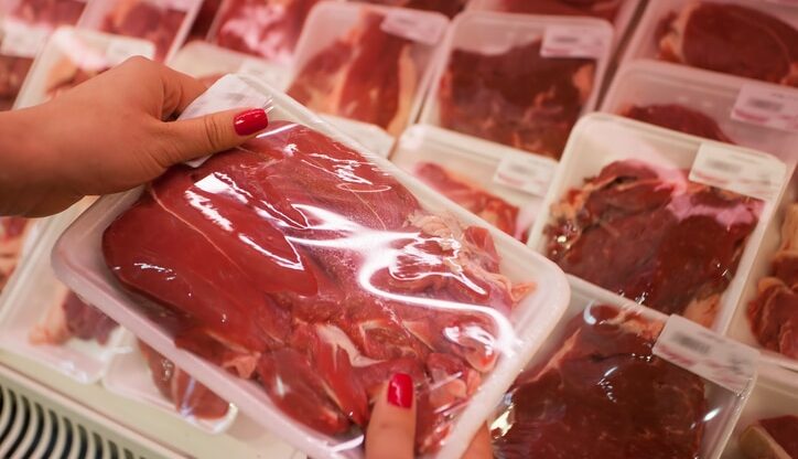 Packaged meat with woman hand in the supermarket