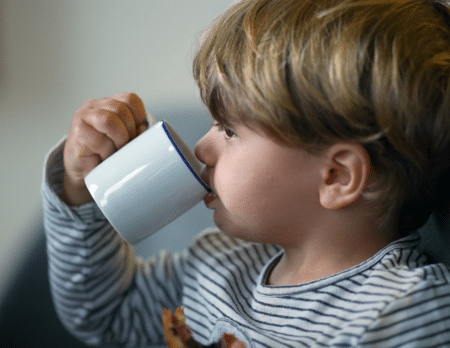 Young baby eating out of a cup.