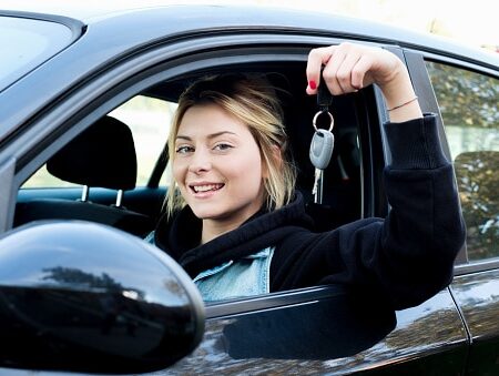 Young girl happy holding car key seated in her new car