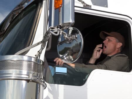Tired at the wheel of 18 wheeler|Safety manager explaining to driver how to use electronic logbook at the office