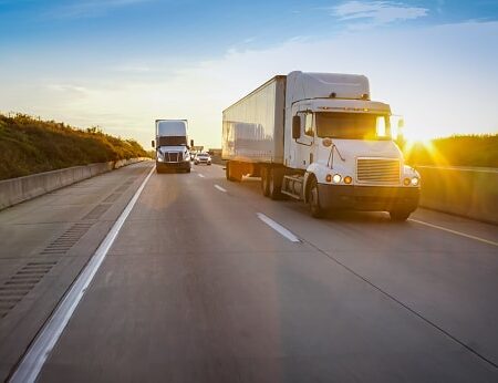 semi tractor trailer driving on the highway in the evening